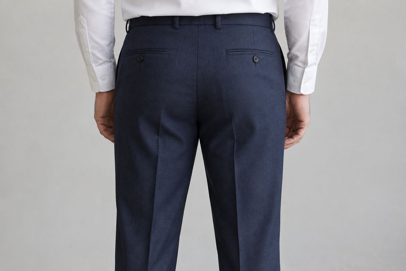 Navy suit trousers seen from behind, with the fabric falling cleanly from the seat to the back of the thigh.