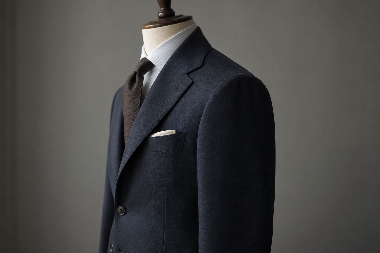 Side view of a buttoned navy jacket with the lapel turning back in a soft curve rather than a flat crease.
