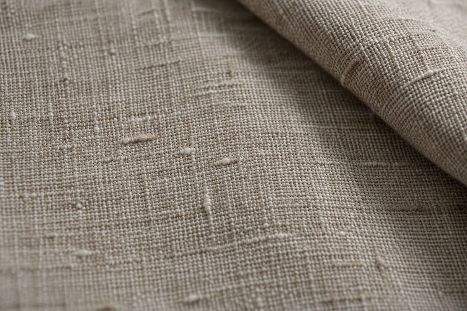 Close-up of stone linen fabric showing the irregular slubs in its yarns.