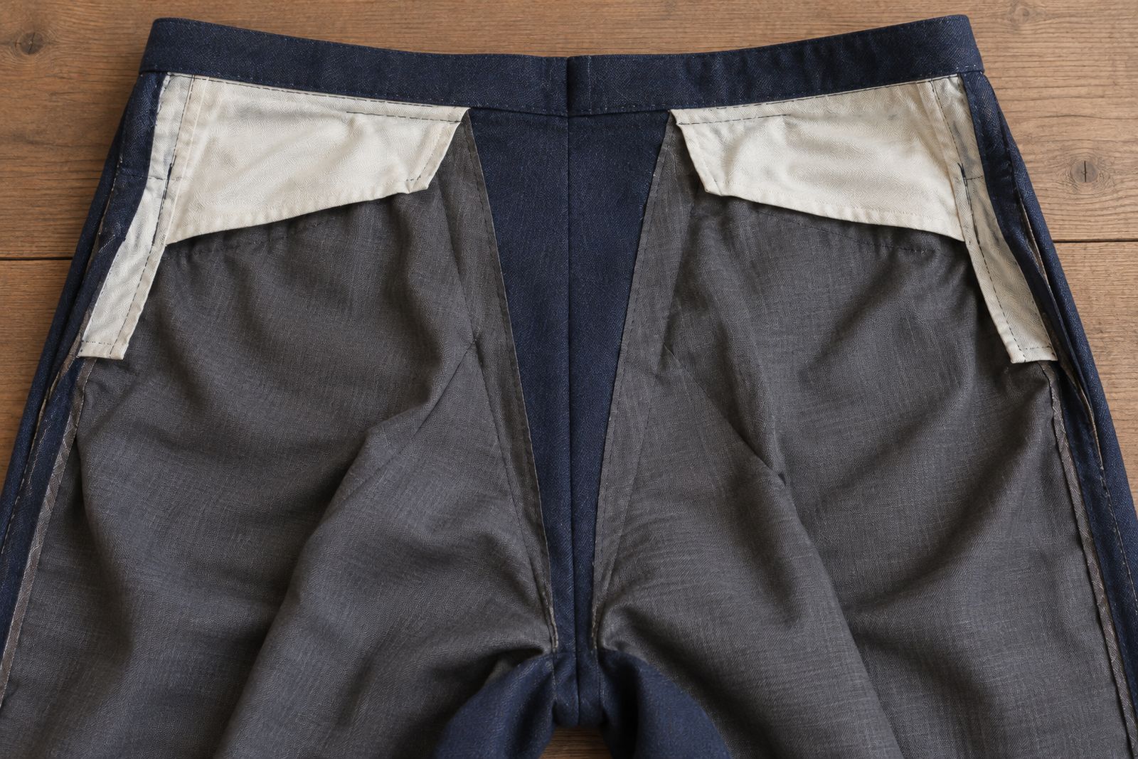 Navy suit trousers turned inside out, showing a wide inlay of spare fabric at the center back seam.