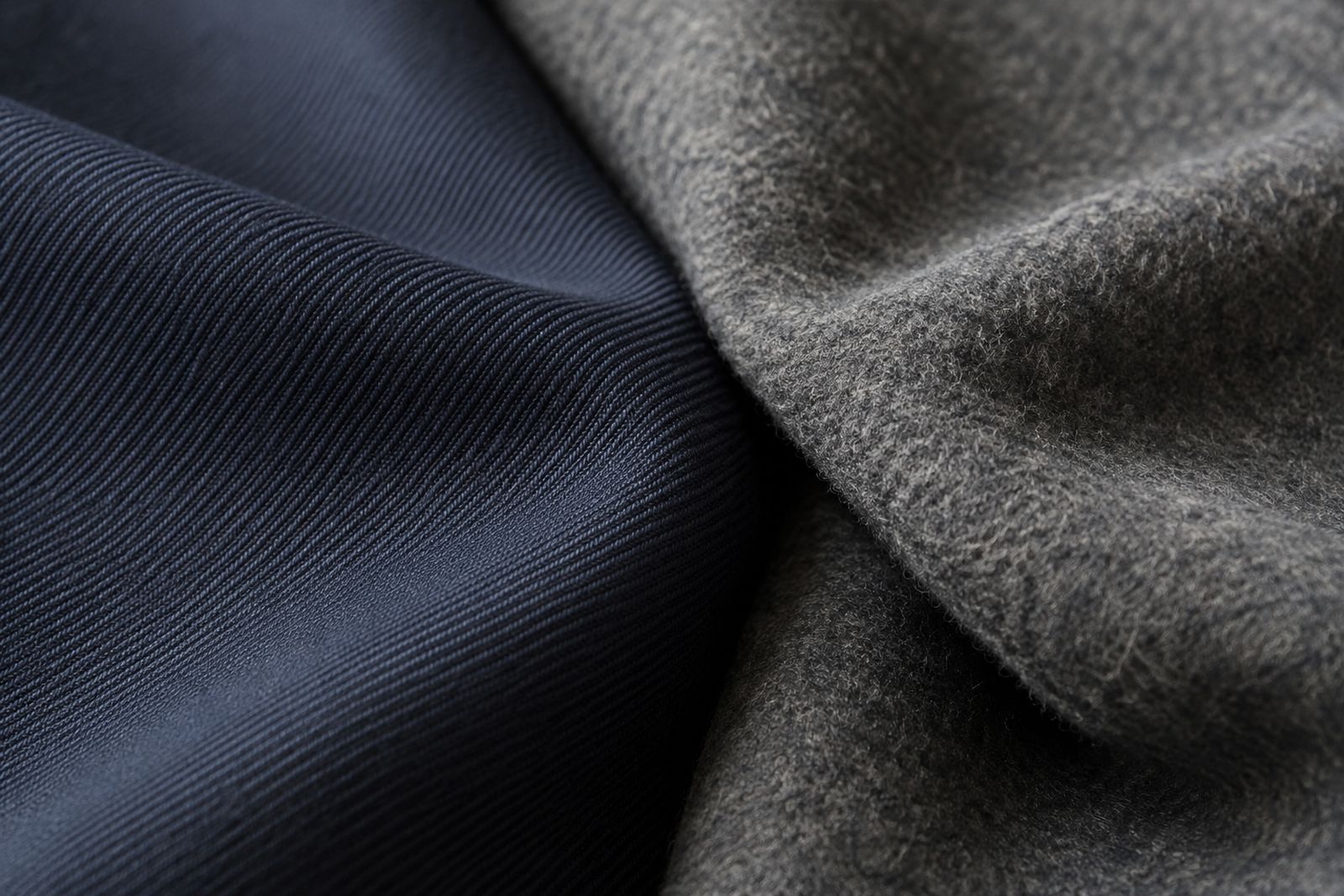 A navy worsted twill with a visible weave beside a gray woolen flannel with a soft nap.