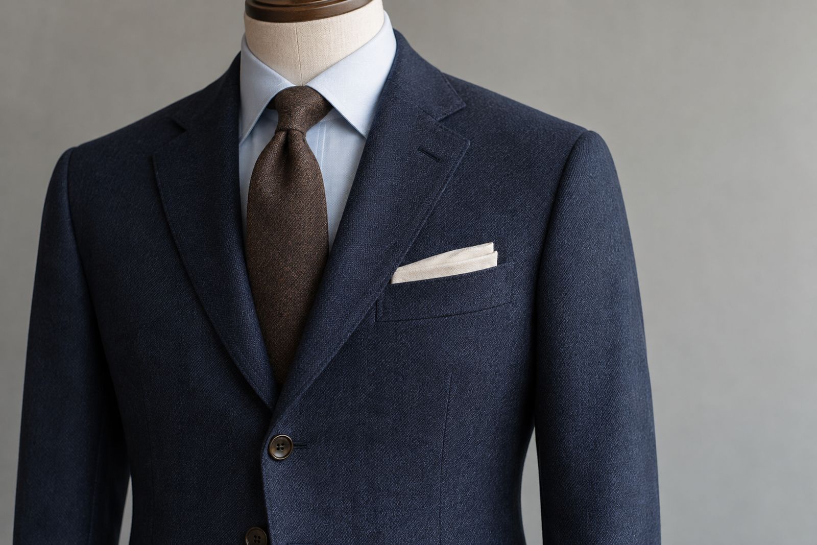 Close-up of the lapel and buttons of a navy ready-to-wear suit jacket.